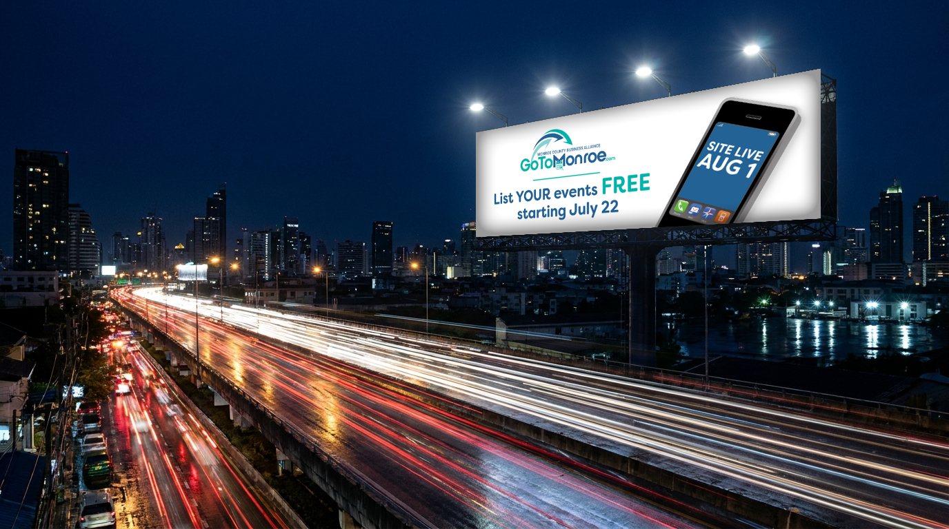 GoToMonroe.com billboard above a city highway at night